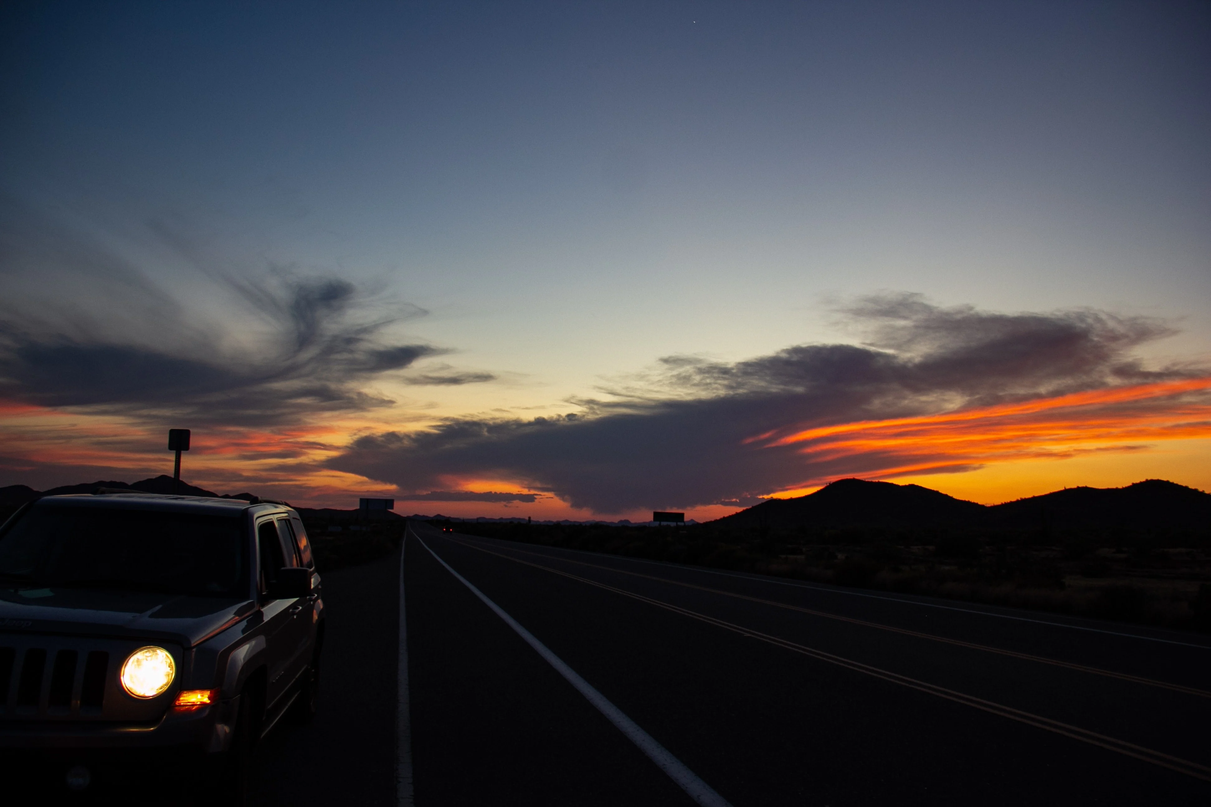 An offroading Jeep Wrangler driving down the Rubicon trail at sunset